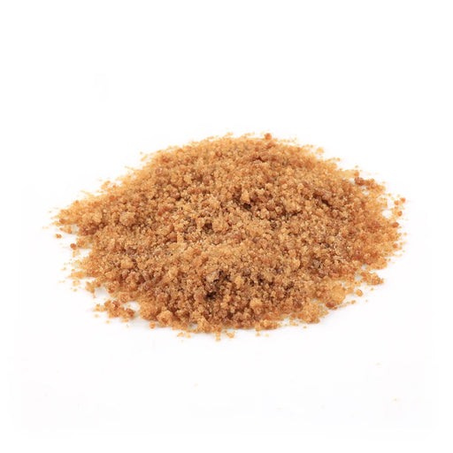 A small mound of coarse brown sugar or brown spice granules on a plain white background.